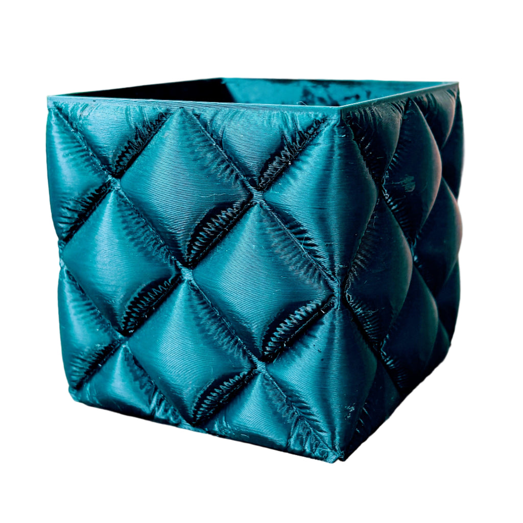 Teal quilted pot on a wooden surface with a colorful background