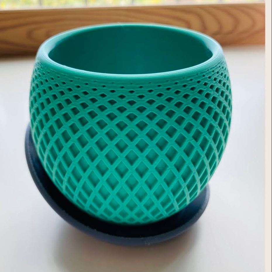 Green textured pot on a white surface with a blurred background